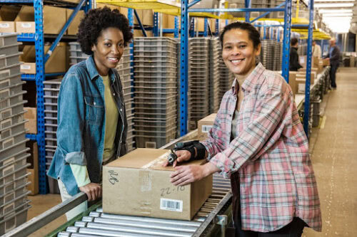 women in warehouse workers by conveyor belt