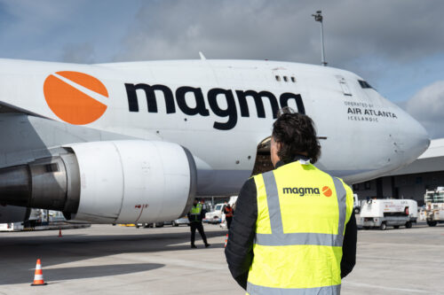 Magma Aviation plane sits on runway. Worker stands in front of it.