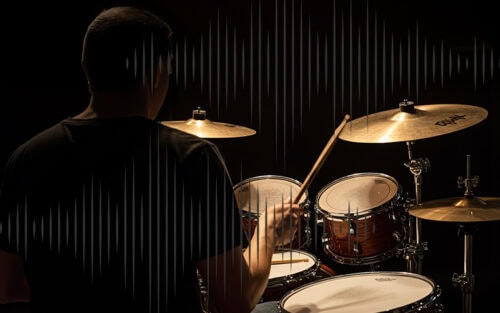 Un baterista tocando una batería con platillos en un espacio de estudio oscuro.