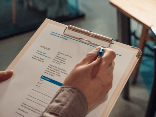 filling out invoice on clipboard