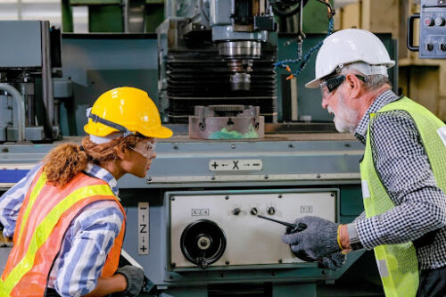 Warehouse workers inspecting manufacturing machinery for quality control